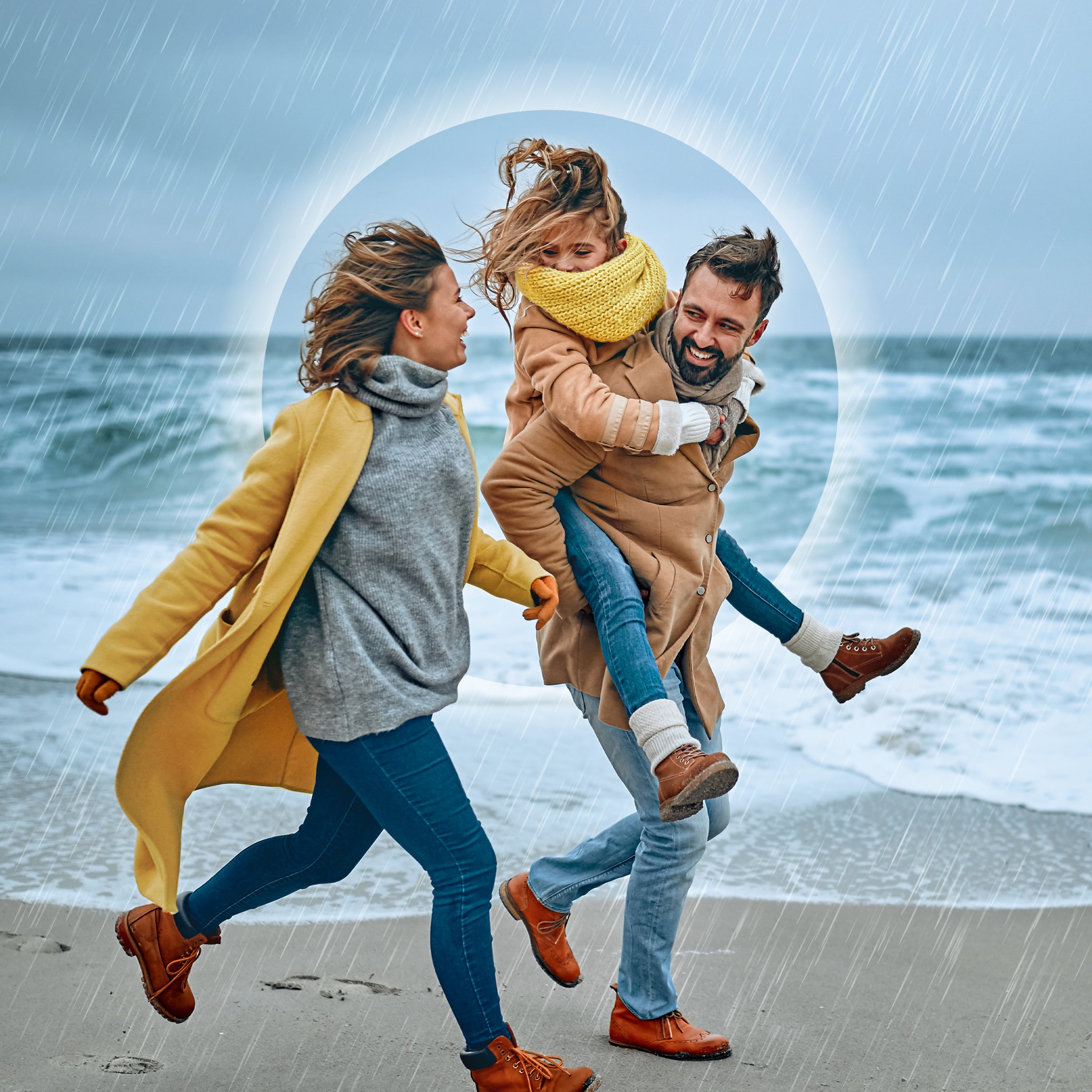 Eine Familie rennt bei Regen den Strand entlang. Der Vater hat die Tochter Huckepack, beide lächeln die Mutter an. Diese lächelt zurück.